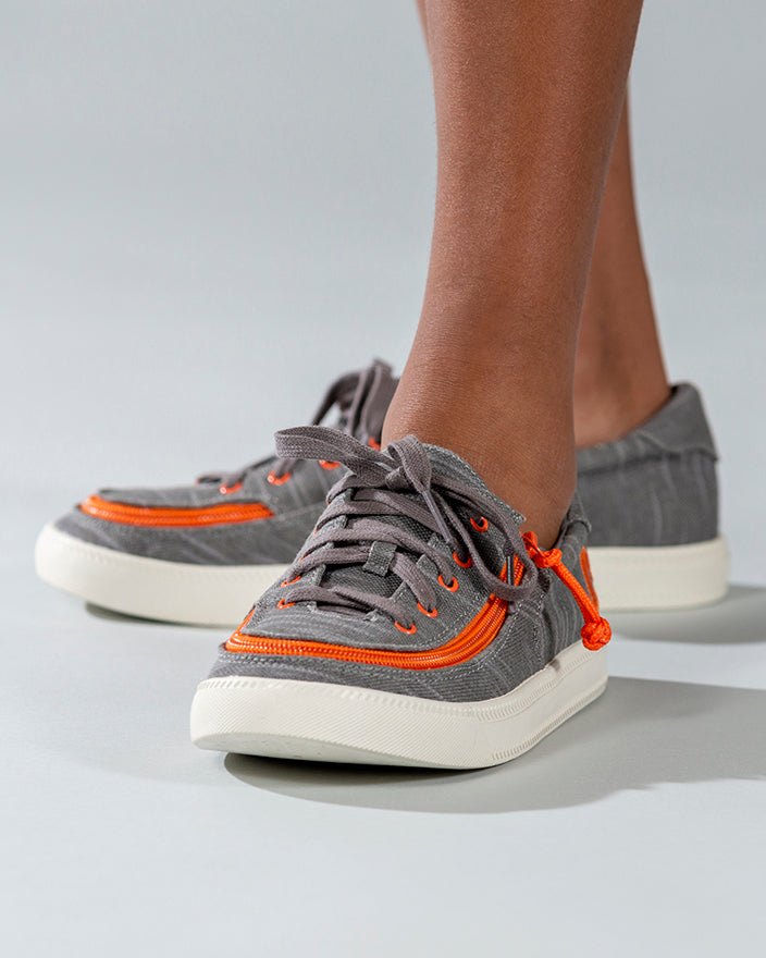 Kid's Grey/Orange BILLY Classic Lace Lows, zipper shoes, like velcro, that are adaptive, accessible, inclusive and use universal design to accommodate an afo. Footwear is medium and wide width, M, D and EEE, are comfortable, and come in toddler, kids, mens, and womens sizing.
